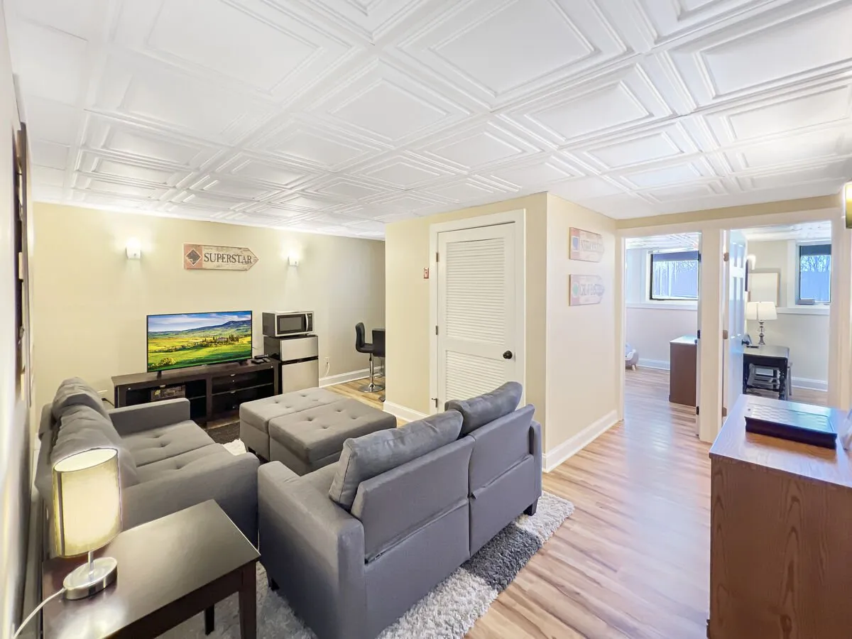 A cozy family room featuring a comfortable sofa, a television mounted on the wall, decorative wall art, and a coffee table in the center. The setting is warm and inviting, perfect for relaxing, watching TV, or spending time together.