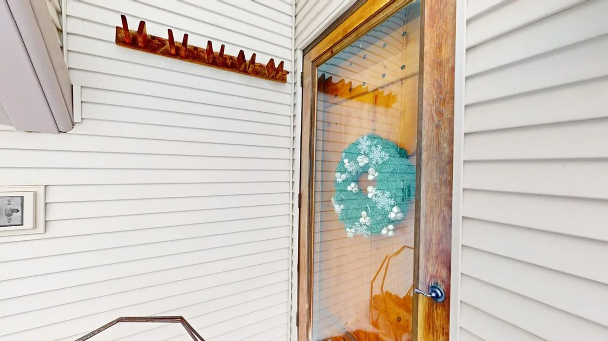 Featuring a decorative wreath and a wooden door set against a textured wall, this image evokes a sense of welcome and arrival. The entryway hints at the transition from outdoor adventures to indoor comfort, making it an ideal introduction to the social spaces within.