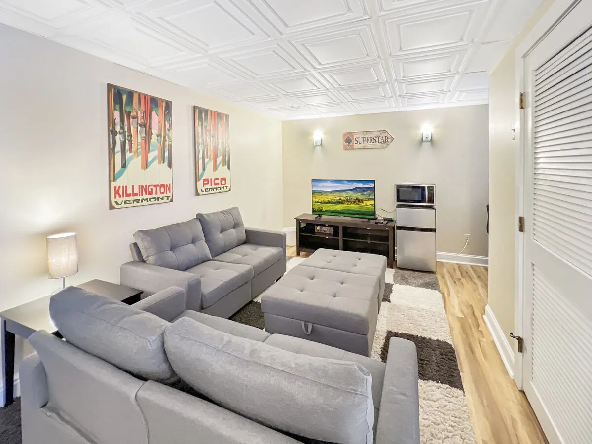 This scene highlights a comfortable living room with a cozy sofa set, artwork on the walls, a television, and a coffee table. The space is casual and designed for relaxation or group activities like movie nights or games, with a warm, welcoming vibe.