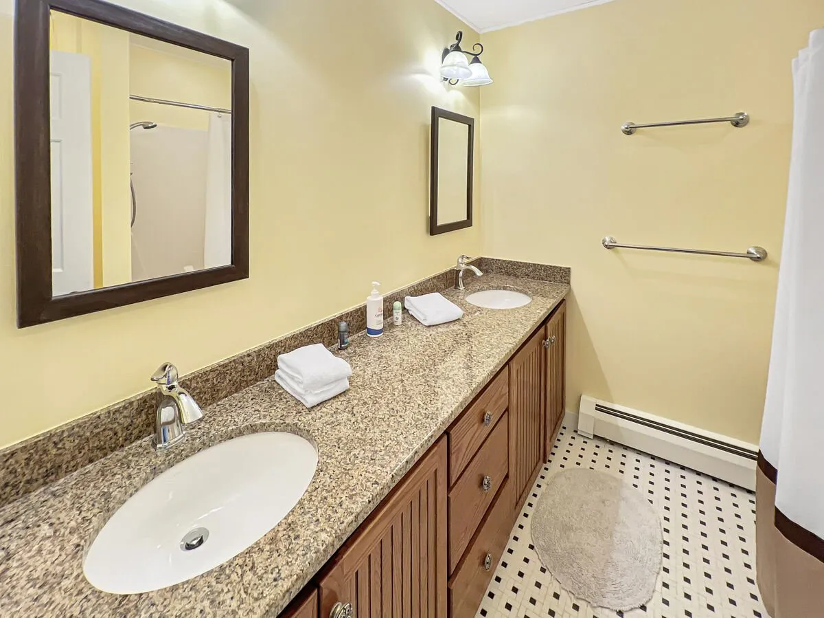 A modern bathroom with a double sink vanity, granite countertop, large mirrors, and plush towels. The space feels functional, calming, and perfect for morning or evening routines.