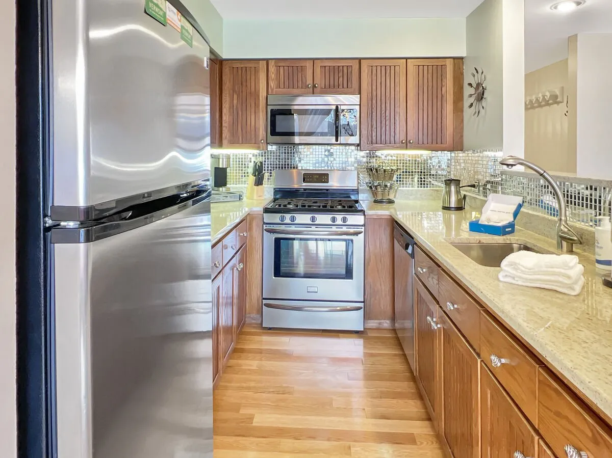 A modern, well-equipped kitchen featuring stainless steel appliances, granite countertops, wooden cabinetry, and a stylish backsplash. The kitchen provides plenty of space for meal preparation and socializing, reflecting the functional and welcoming character highlighted in the text.